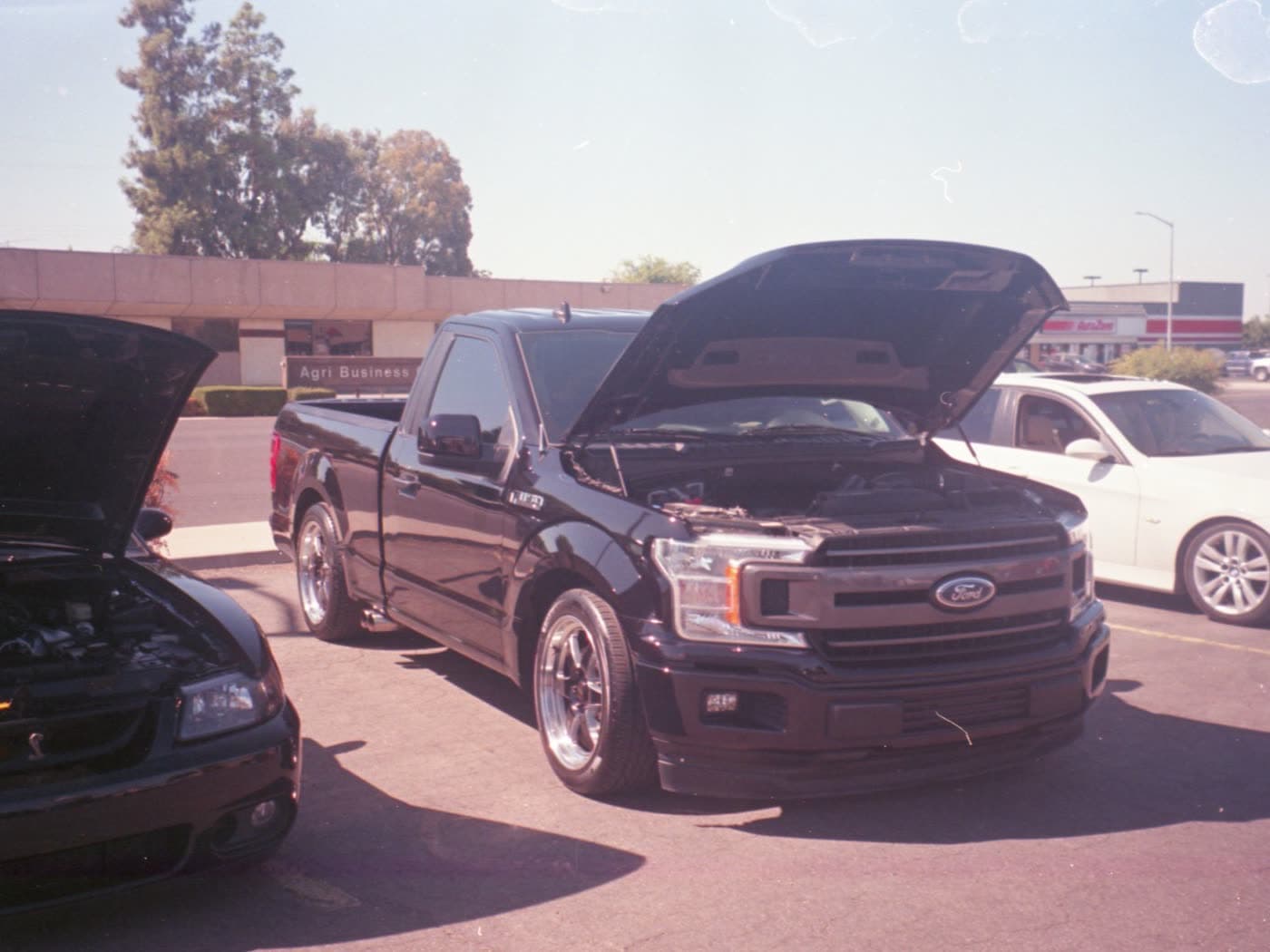 A pickup truck with the hood up in a parking lot, waiting on a mobile mechanic